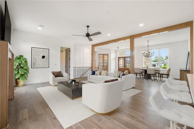 Living area with light wood finished floors, a chandelier, recessed lighting, ceiling fan, and baseboards | Image 13