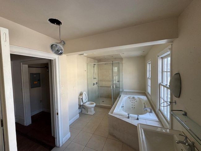 Bathroom with tile patterned flooring, toilet, baseboards, a shower stall, and a whirlpool tub | Image 4