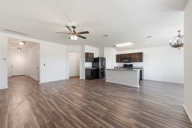 Unfurnished living room featuring a ceiling fan, dark wood finished floors, and a chandelier | Image 5