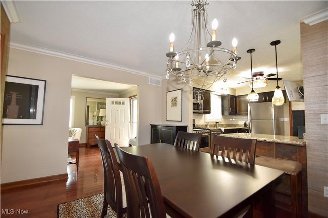 Dining space featuring dark wood finished floors, a chandelier, baseboards, and ornamental molding | Image 9