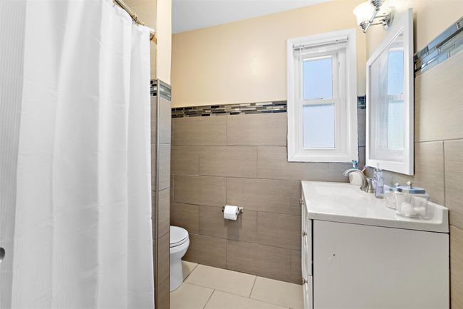 Full bath with vanity, tile walls, toilet, and tile patterned floors | Image 30