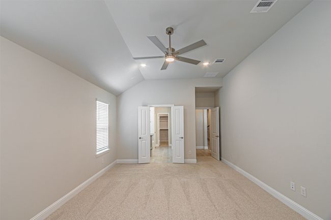 Unfurnished bedroom featuring vaulted ceiling, light colored carpet, a spacious closet, and ceiling fan | Image 23