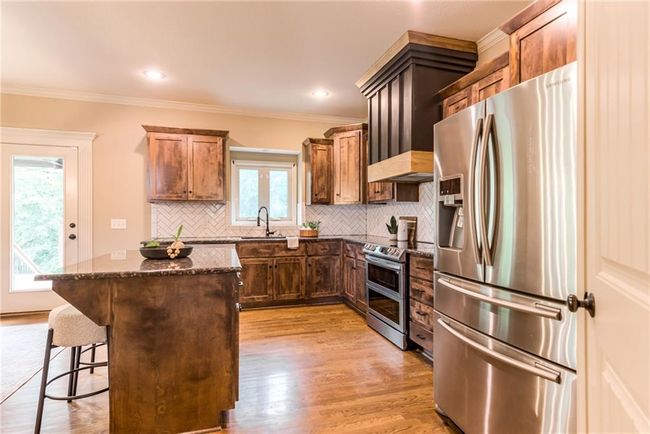 Kitchen with appliances with stainless steel finishes, a kitchen island, dark stone counters, decorative backsplash, and crown molding | Image 7