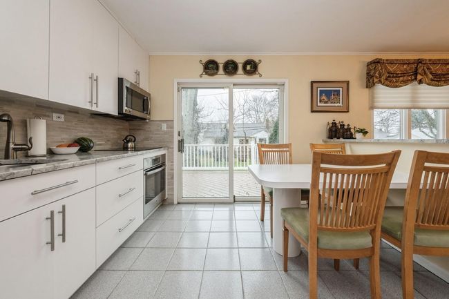 Kitchen featuring crown molding, stainless steel appliances, decorative backsplash, a sink, and white cabinets | Image 5