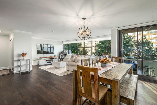 Dining room with ornamental molding, dark wood-type flooring, plenty of natural light, and a chandelier | Image 11