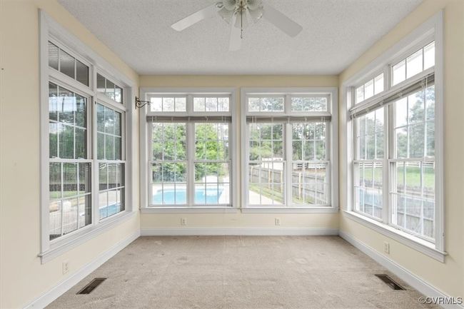 Unfurnished sunroom featuring carpet floors, a textured ceiling, baseboards, and french doors | Image 23