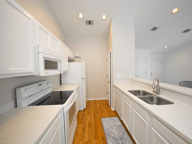 Kitchen featuring visible vents, a sink, and white appliances | Image 14