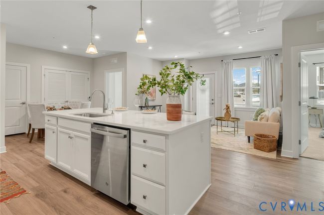 Kitchen with stainless steel dishwasher, white cabinetry, a kitchen island with sink, light wood-style flooring, and recessed lighting | Image 7