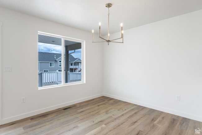 Spare room with a chandelier, light wood-style flooring, and baseboards | Image 5