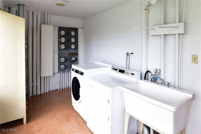 Clothes washing area featuring a sink, washing machine and dryer, and concrete block wall | Image 29