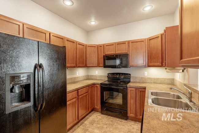 Kitchen with black appliances, light countertops, recessed lighting, and brown cabinetry | Image 5