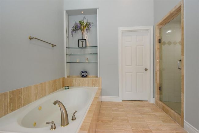 Large bathroom featuring a built-in bathtub, new fixtures, a separate glass-enclosed shower, tiled flooring, and a built-in shelving niche | Image 18