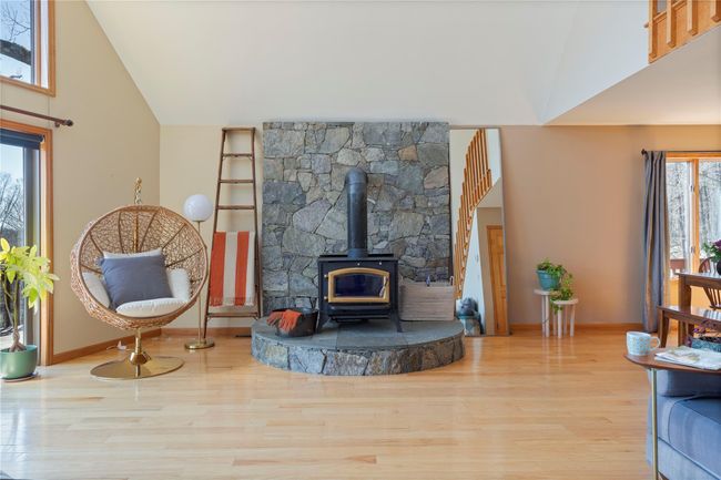 Living area with baseboards, high vaulted ceiling, wood finished floors, and a wood stove | Image 6