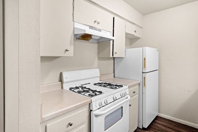 Kitchen with white appliances, light countertops, under cabinet range hood, and baseboards | Image 7