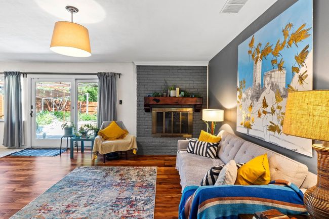 The bright and spacious living room boasts a striking cornered fireplace and plenty of room to lounge. Notice the Acacia wood floors! | Image 23