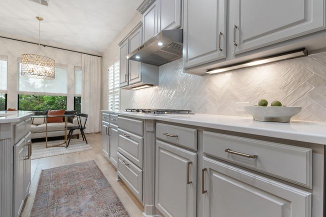 Remodeled Kitchen featuring ventilation hood, a chandelier, light countertops, and decorative backsplash | Image 10