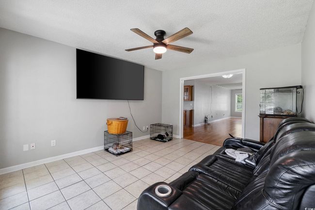 Living area with a ceiling fan, tile patterned floors, a textured ceiling, and baseboards | Image 34