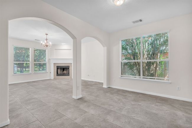 Unfurnished living room with arched walkways, a tile fireplace, and a chandelier | Image 5