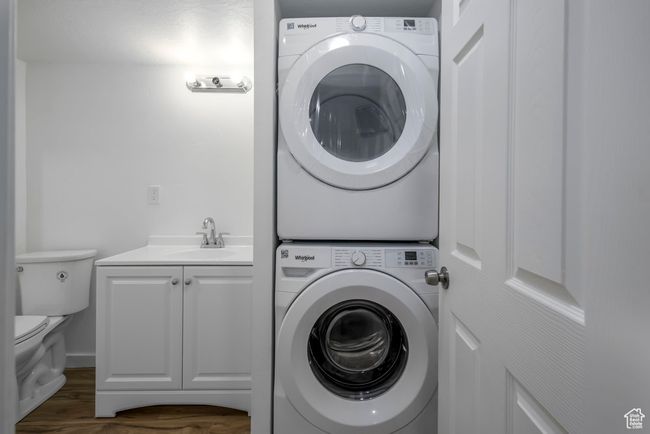 Washroom featuring a sink, stacked washing maching and dryer, laundry area, and dark wood-style flooring | Image 33