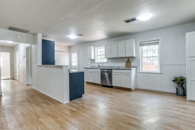 Kitchen with dishwasher, light wood-style flooring, light stone countertops, and a peninsula | Image 8