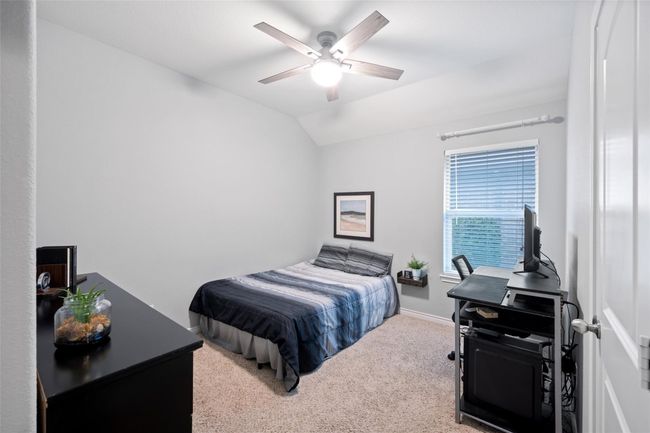 Bedroom with baseboards, carpet flooring, an office area, vaulted ceiling, and ceiling fan | Image 13