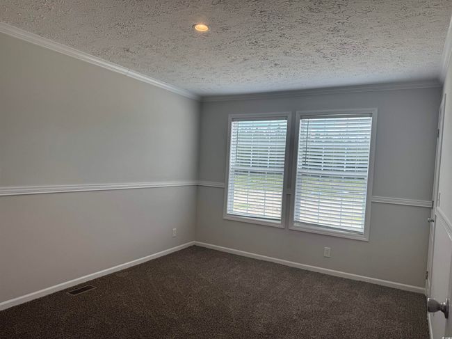 Empty room featuring a textured ceiling, dark carpet, and crown molding | Image 26