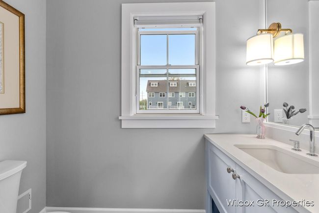 Convenient half bath features quartz counters, custom vanity, and loads of natural light. | Image 22