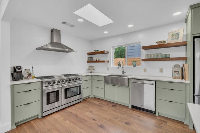 Kitchen featuring wall chimney exhaust hood, appliances with stainless steel finishes, and green cabinets | Image 17