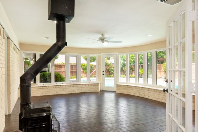 Unfurnished sunroom featuring a wood stove, wood finished floors, brick wall, and recessed lighting | Image 29