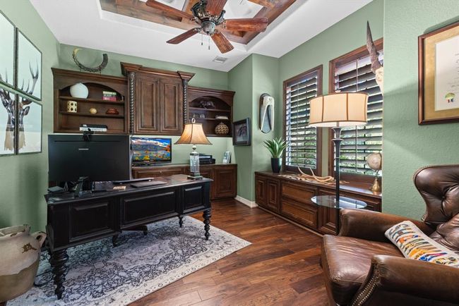 Working from home? This executive office is inviting. Behind the French doors, the office boasts a custom tiered ceiling, hand-crafted built-in desk, bench seat, & plantation shutters...the workmanship is incredible and noticeably sets itself apart from other home in the area... | Image 16