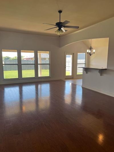 Spare room with dark wood-type flooring, ceiling fan with notable chandelier, and ornamental molding | Image 3