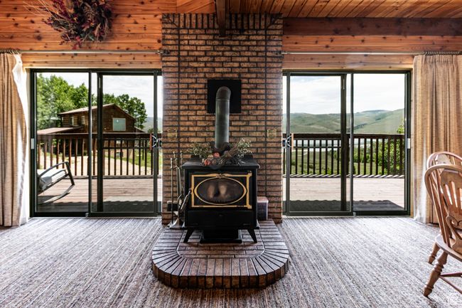 Carpeted living area featuring wood walls, a wood stove, plenty of natural light, wooden ceiling, and a mountain view | Image 4