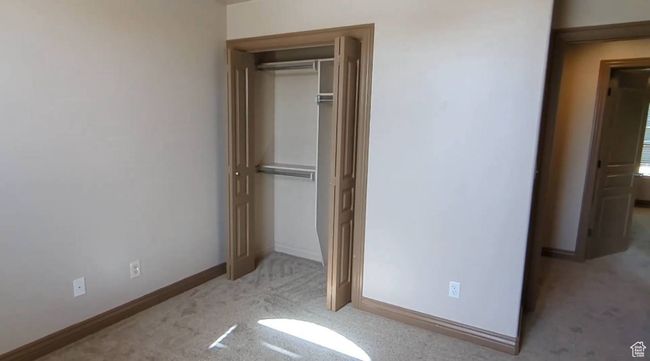 Unfurnished bedroom with carpet flooring, a closet, and baseboards | Image 24