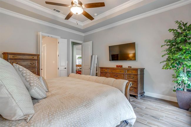 Bedroom featuring wood finish floors, ornamental molding, a raised ceiling, and a ceiling fan | Image 30