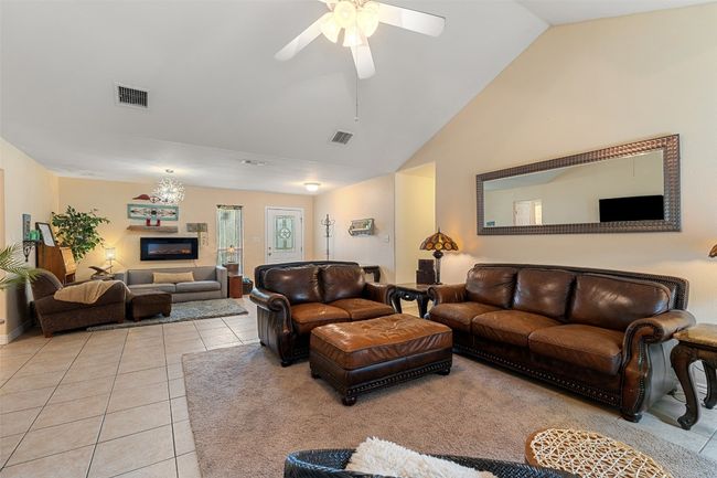 Living room featuring light tile patterned flooring, a ceiling fan, and high vaulted ceiling | Image 12