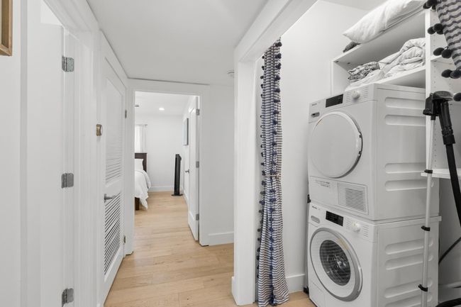 Laundry room featuring laundry area, stacked washer and dryer, light wood finished floors, and baseboards | Image 27