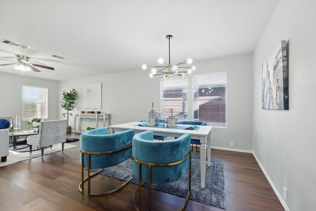 Dining space with dark wood-style flooring, a chandelier, and ceiling fan | Image 9