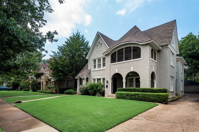 French country home featuring brick siding, a front yard, and roof with shingles | Image 4