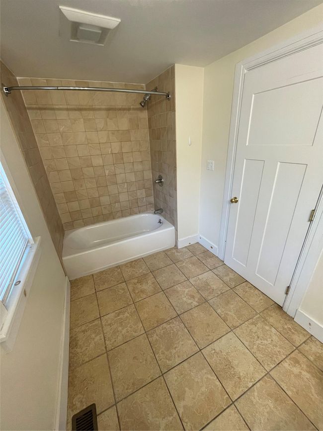 Bathroom featuring washtub / shower combination, baseboards, and tile patterned floors | Image 10
