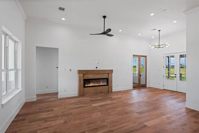 This inviting living area features elegant LVP floors, a cozy fireplace, and abundant natural light with charming French doors. | Image 20