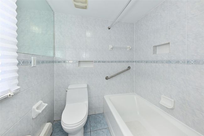 Full bathroom with bathtub / shower combination, toilet, tile patterned flooring, and tile walls | Image 12