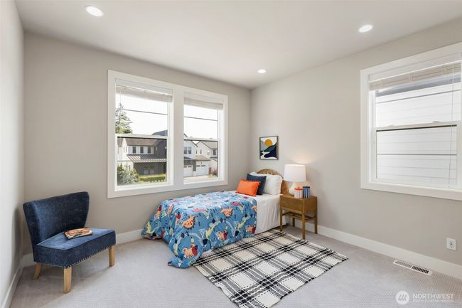 This cheerful upstairs bedroom offers a bright and versatile space with large windows, plush carpeting, and a welcoming layout. Whether used as a bedroom, guest space, or creative nook, it’s filled with natural light and cozy charm. | Image 35