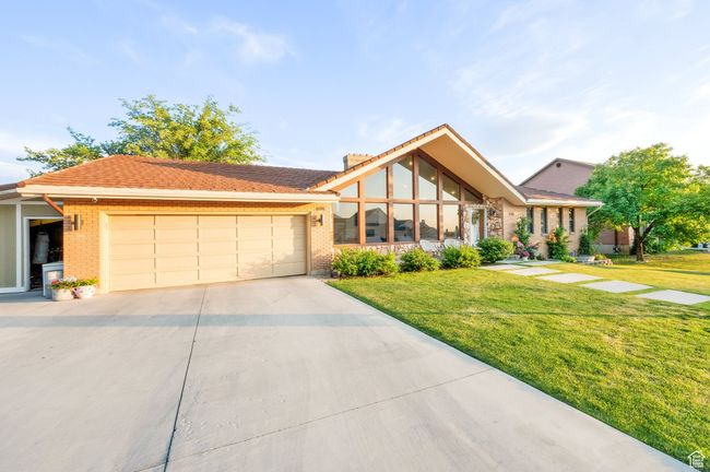 View of front facade featuring a garage, driveway, a front yard, and brick siding | Image 39