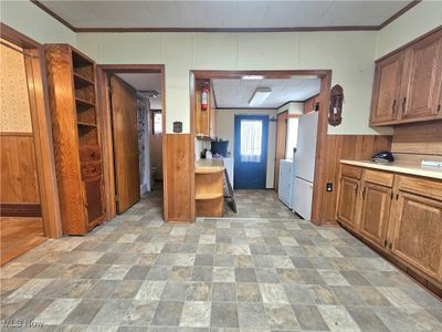 Kitchen with white fridge, crown molding, and light tile floors | Image 2