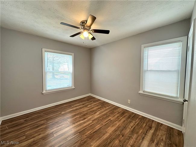 Unfurnished room featuring baseboards, dark wood-style flooring, a textured ceiling, and a healthy amount of sunlight | Image 6