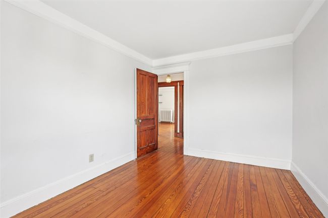 Empty room featuring radiator heating unit, wood-type flooring, and baseboards | Image 22