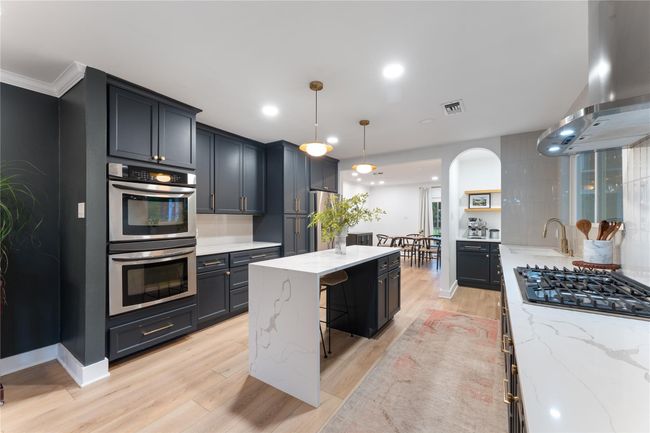 Renovated kitchen features waterfall island, quartz countertops, updated soft close cabinets, and 5-burner gas range | Image 9