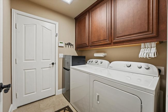 Laundry room with separate washer and dryer, baseboards, light tile patterned flooring, and cabinet space | Image 24