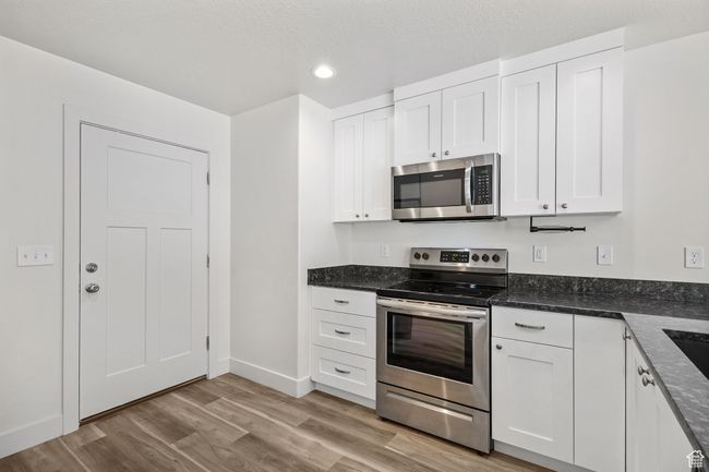 Kitchen with appliances with stainless steel finishes, white cabinets, Granite countertops, luxury vinyl plank, flooring recessed lighting, and baseboards | Image 10