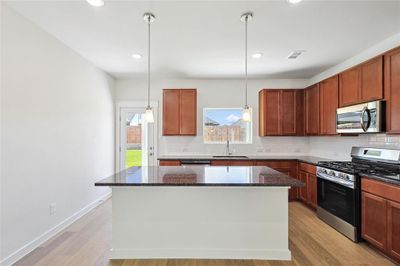 Kitchen featuring hanging light fixtures, light hardwood / wood-style floors, a kitchen island, stainless steel appliances, and sink | Image 2